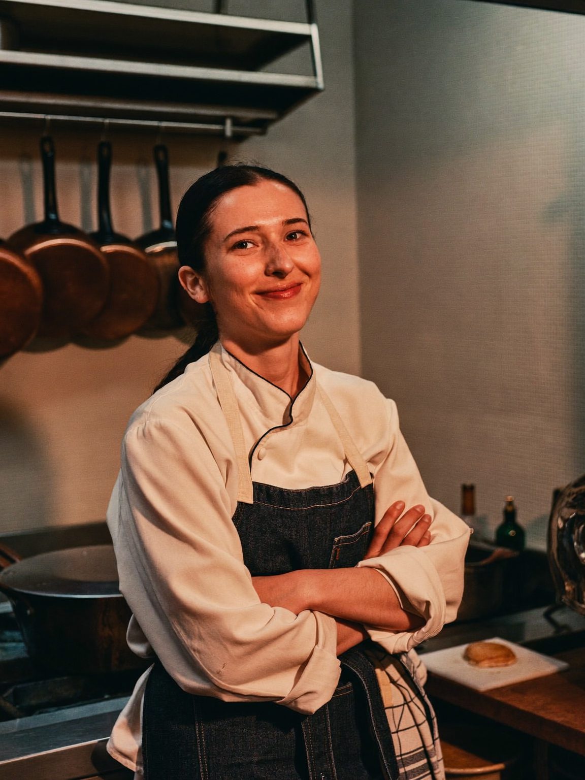 Camille, la cheffe, bras croisés dans sa cuisine