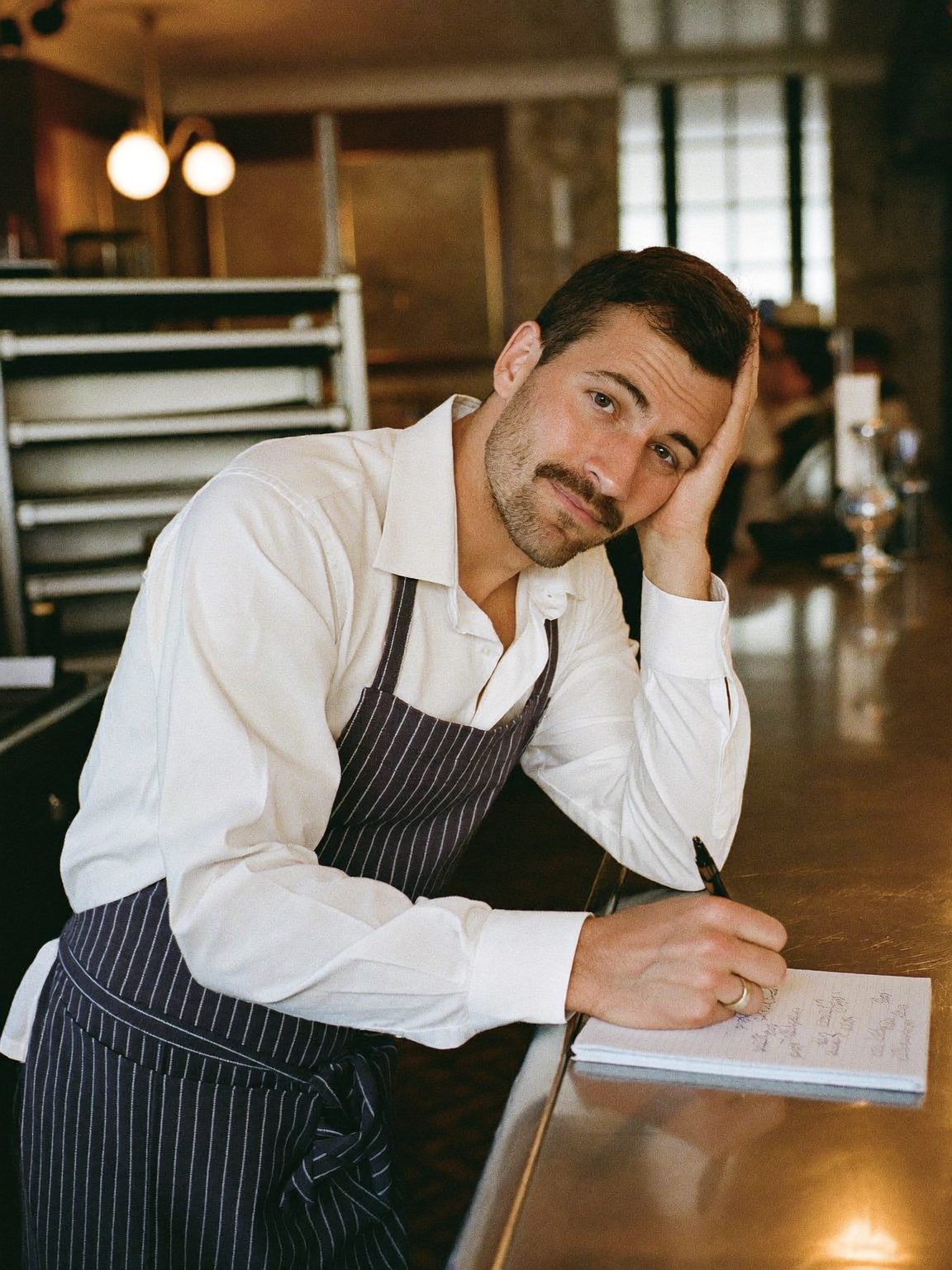 Hugo, au comptoir, devant le cahier de réservations