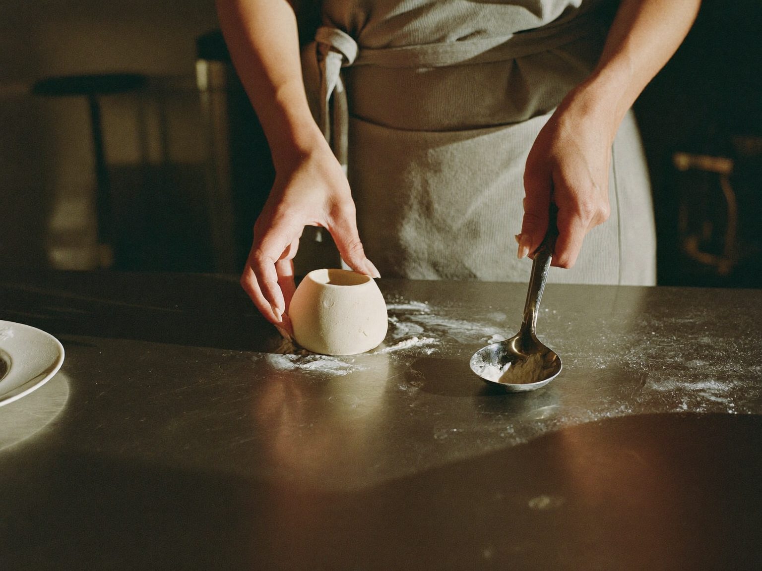 Mains de la cheffe moulant une quenelle entre deux cuillères